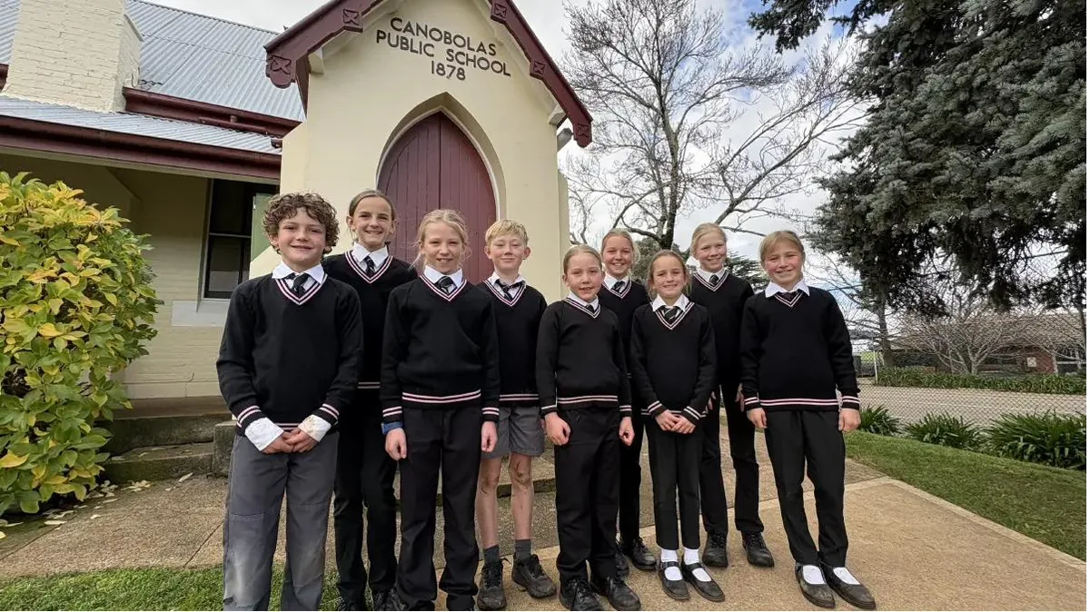 Nine Canobolas Public School students in uniform outside the school's historic 1878 building
