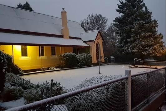 Canobolas Public School buildings under snow at dusk in winter, warm light in the windows